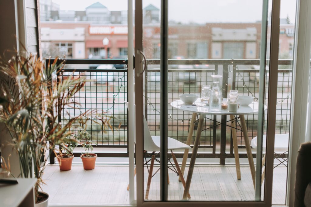 a small wooden table with two chairs sits on an apartment balcony